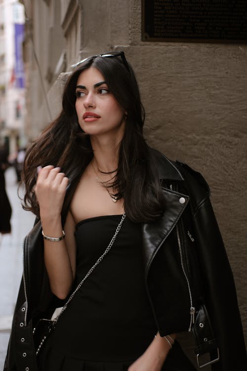 A woman in a black dress and leather jacket