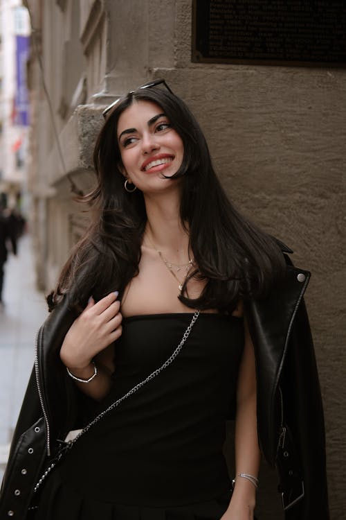 A woman in a black dress and leather jacket