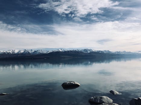 Serene landscape of Lake Pukaki with snow-capped mountains and a tranquil sky in Canterbury, New Zealand.