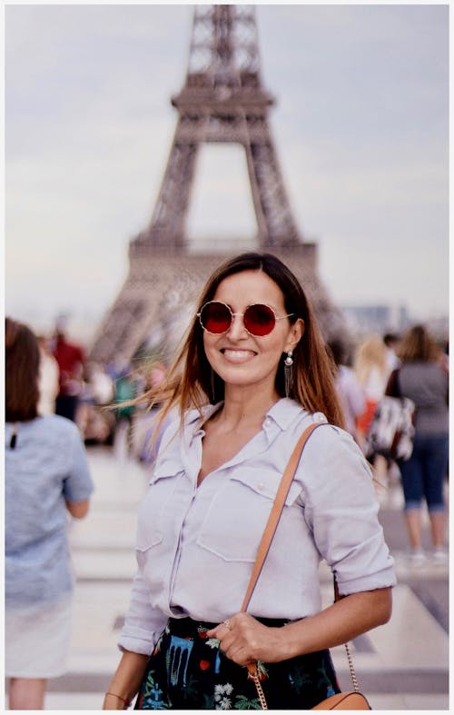 Foto De Foco Seletivo De Uma Mulher Sorridente Posando Com Uma Multidão De Pessoas E A Torre Eiffel Ao Fundo