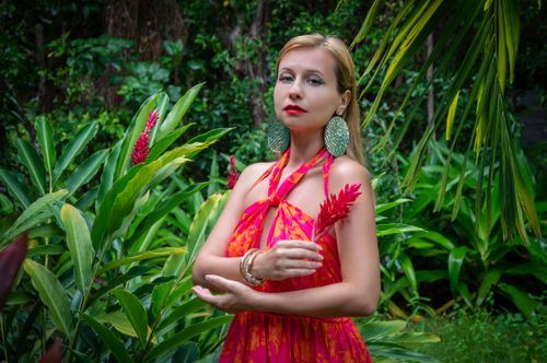 Free Woman in colorful dress with tropical plants, evoking exotic vibes. Stock Photo