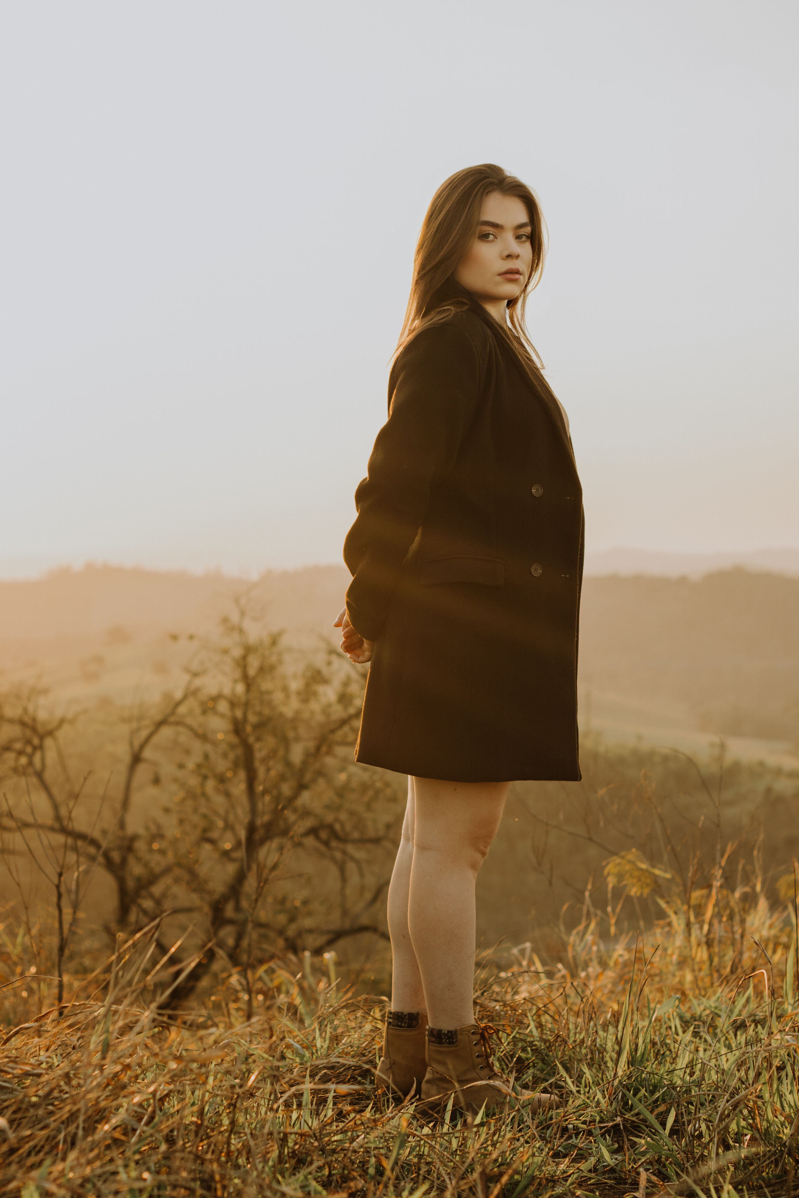 A Woman in a Coat Standing on a Meadow in Autumn · Free Stock Photo