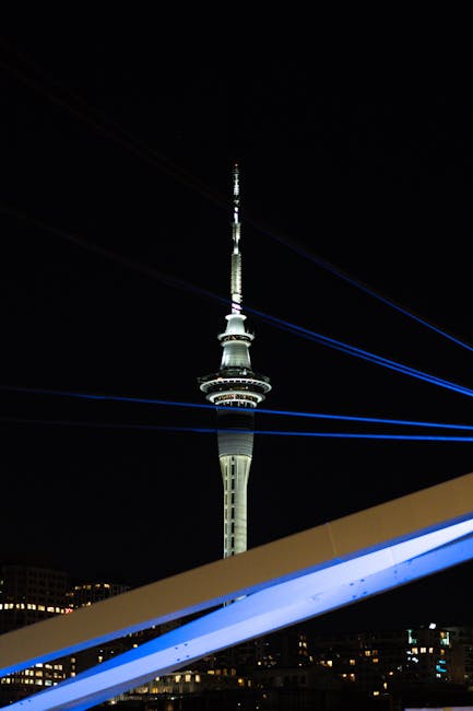 Sky Tower in Auckland, New Zealand, illuminated against the night sky with bridge accents.