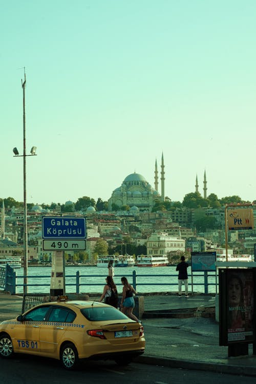 A yellow taxi is parked near a bridge