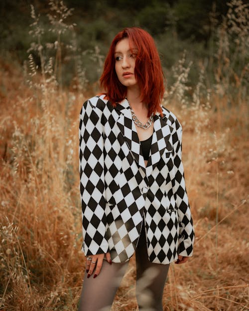 A woman with red hair and black and white checkered jacket