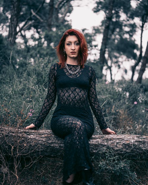 A woman in a black dress sitting on a log