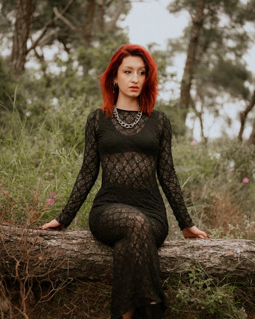 A woman with red hair sitting on a log