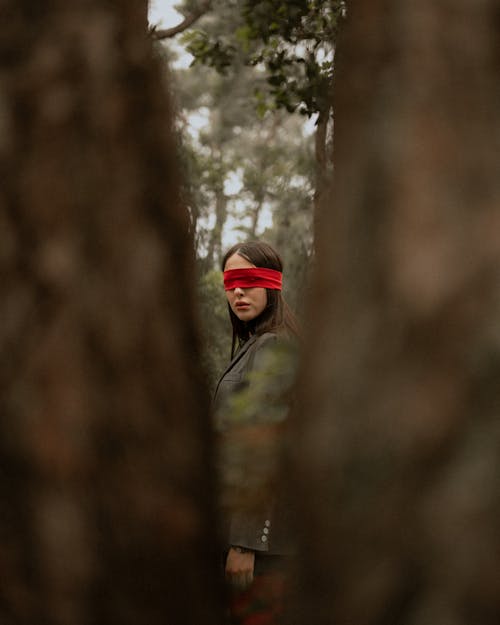 A woman with a red blindfold in the woods