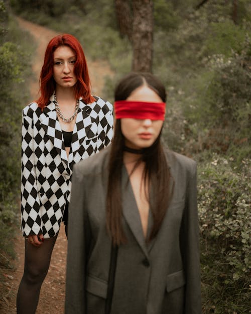 Two women in red and black checkered suits standing in the woods