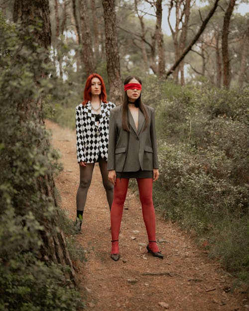 Two women in red tights and plaid jackets are standing on a path