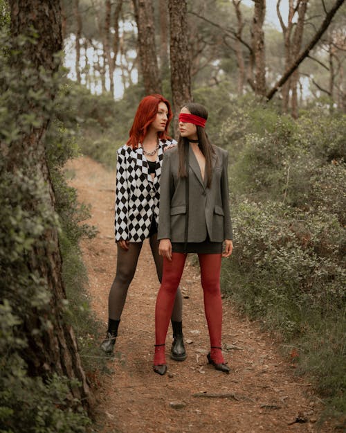 Two women in red tights and stockings standing in the woods