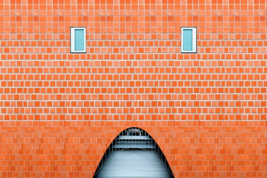 Orange brick facade with two blue windows and an archway entrance.