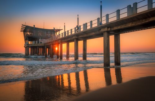 Free Beautiful sunrise at the Durban pier with waves gently lapping the shore in a serene coastal scene. Stock Photo