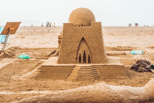 A detailed sandcastle sculpture resembling a historical temple or tomb on a sunny beach, showcasing artistic sandcraft.