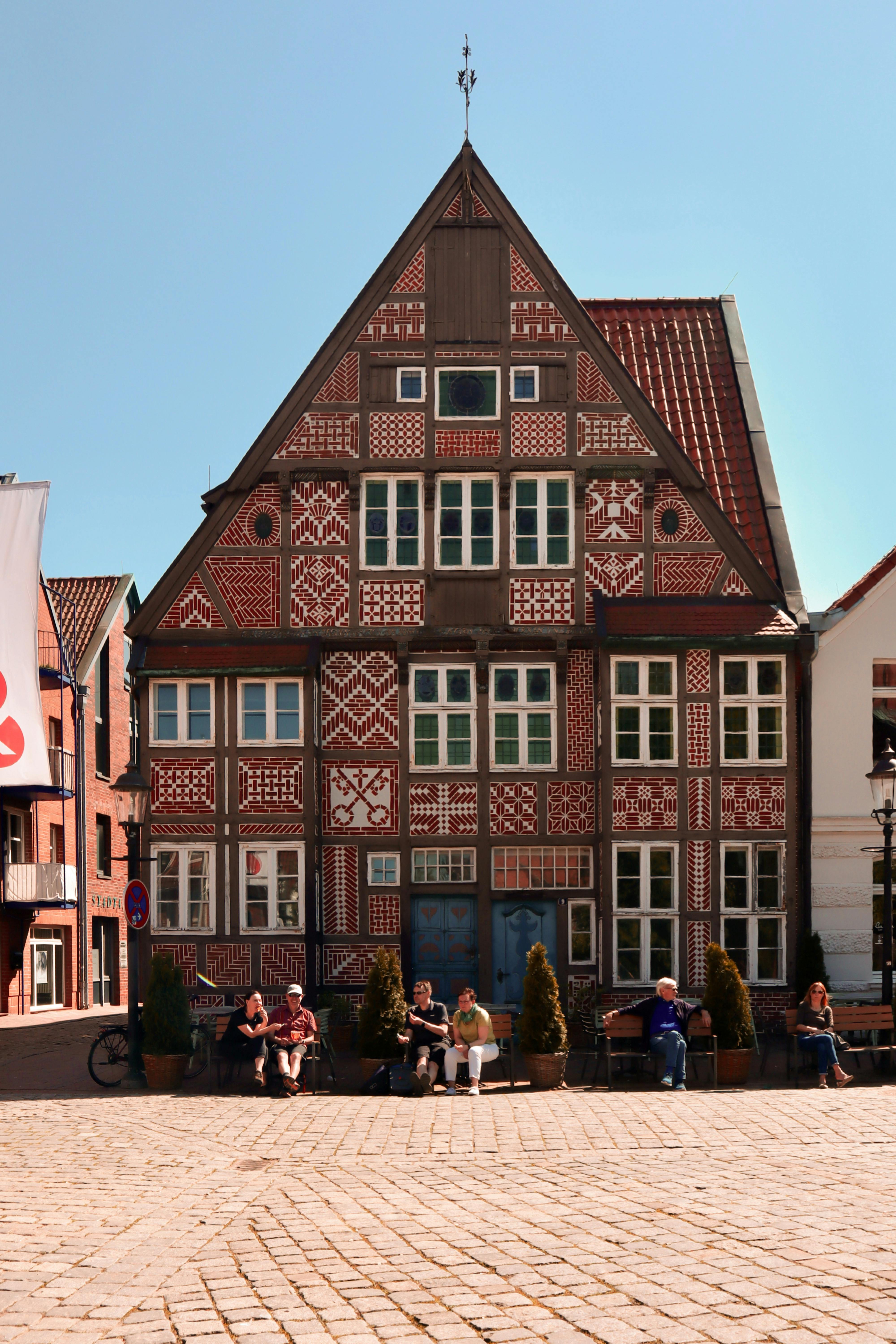 Charming half-timbered building in Buxtehude's old town, featuring people sitting on a sunny day.