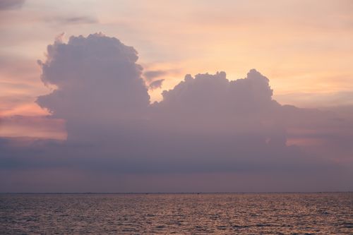 Free A tranquil ocean sunset with dramatic clouds reflecting beautiful colors. Stock Photo