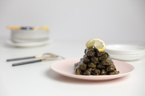 Free Appetizing stuffed grape leaves on a plate with a lemon wedge, perfect for Mediterranean cuisine. Stock Photo