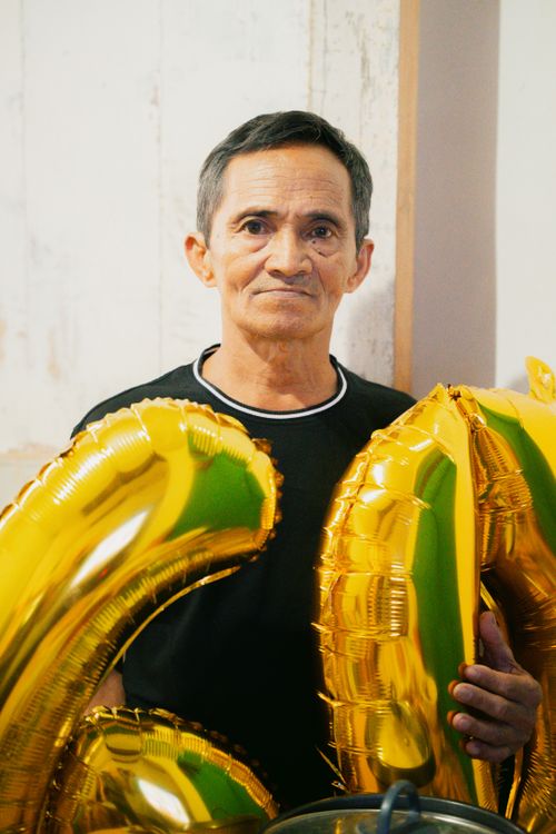 Free Senior man posing with golden birthday balloons in a casual portrait. Stock Photo