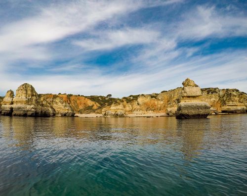 Free Beautiful rock formations along the Algarve coast, Portugal under a cloudy sky. Stock Photo