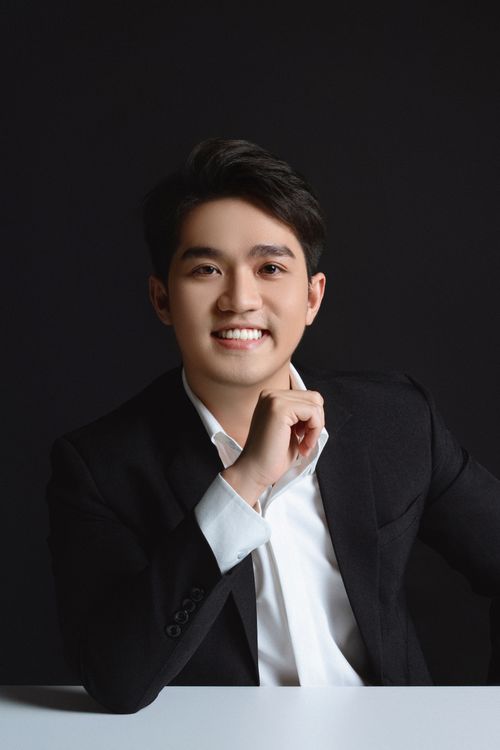 Free Young man in black suit smiling confidently in a studio setting. Stock Photo
