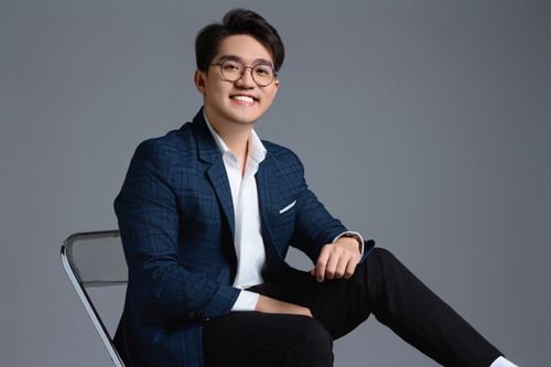 Free Confident Asian businessman in a stylish blue suit, sitting and smiling in a studio setting. Stock Photo
