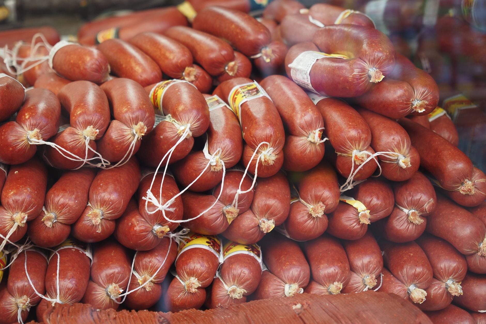 A stack of fresh sausages neatly arranged at a market, showcasing rich colors and textures of cured meats.