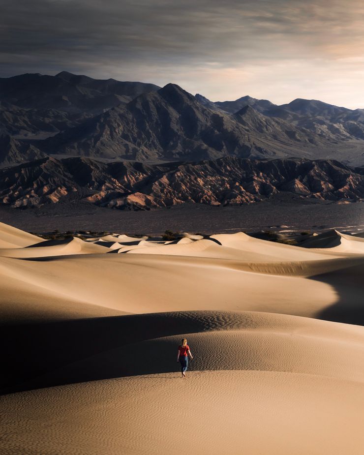 Lone walker crossing rippled dunes below a mountain ridge, photo by Trace Hudson on Pexels