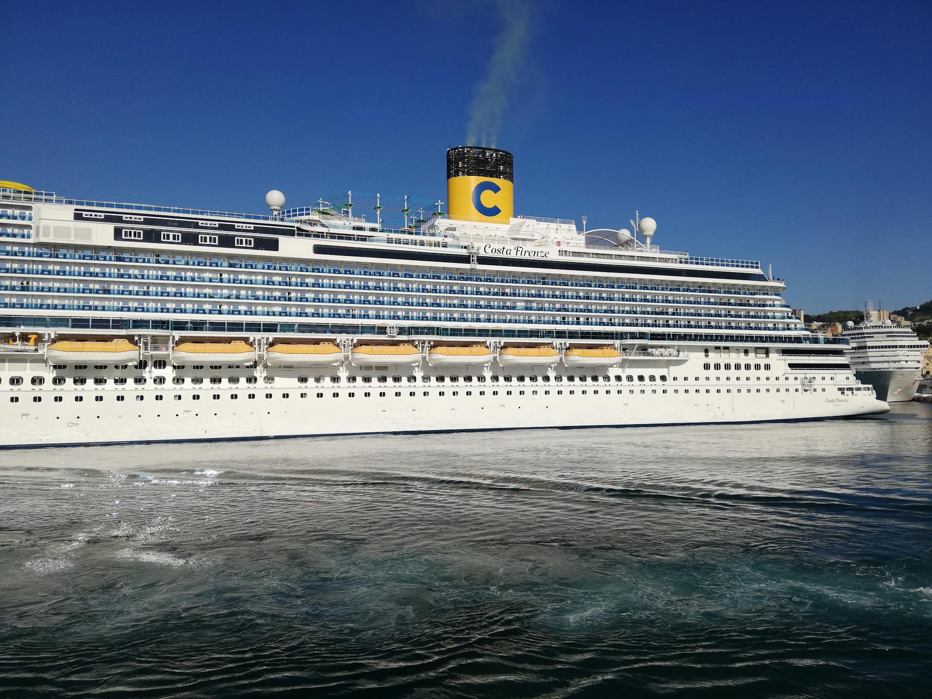 View of Costa Firenze cruise ship sailing near the coast under a clear blue sky.