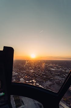 Scenic aerial view of a city skyline at sunset from an aircraft window, showcasing a vibrant sky.