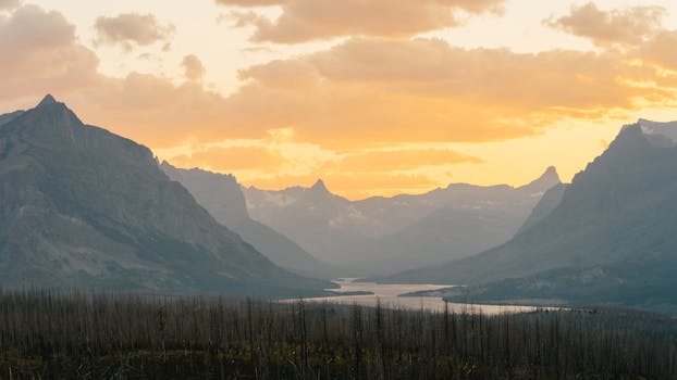 Vibrant sunrise at Glacier National Park, highlighting stunning mountain landscapes and serene river views.