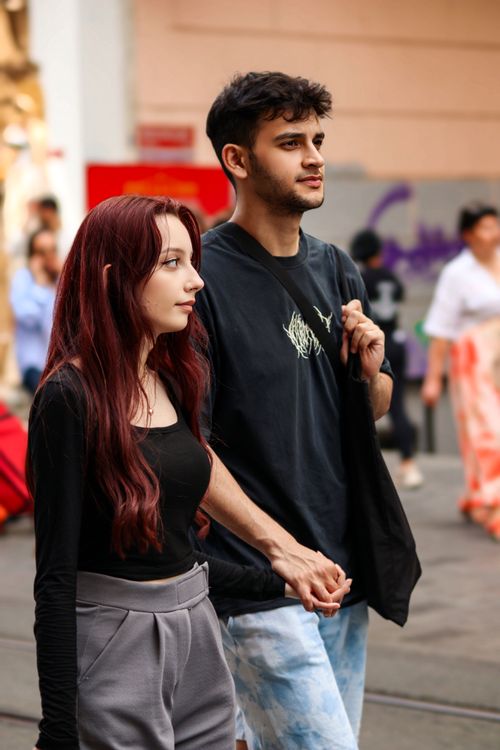 Free A young couple walks hand in hand on a busy city street, embodying urban romance and connection. Stock Photo