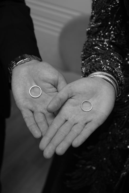Black and white photo of two hands holding rings