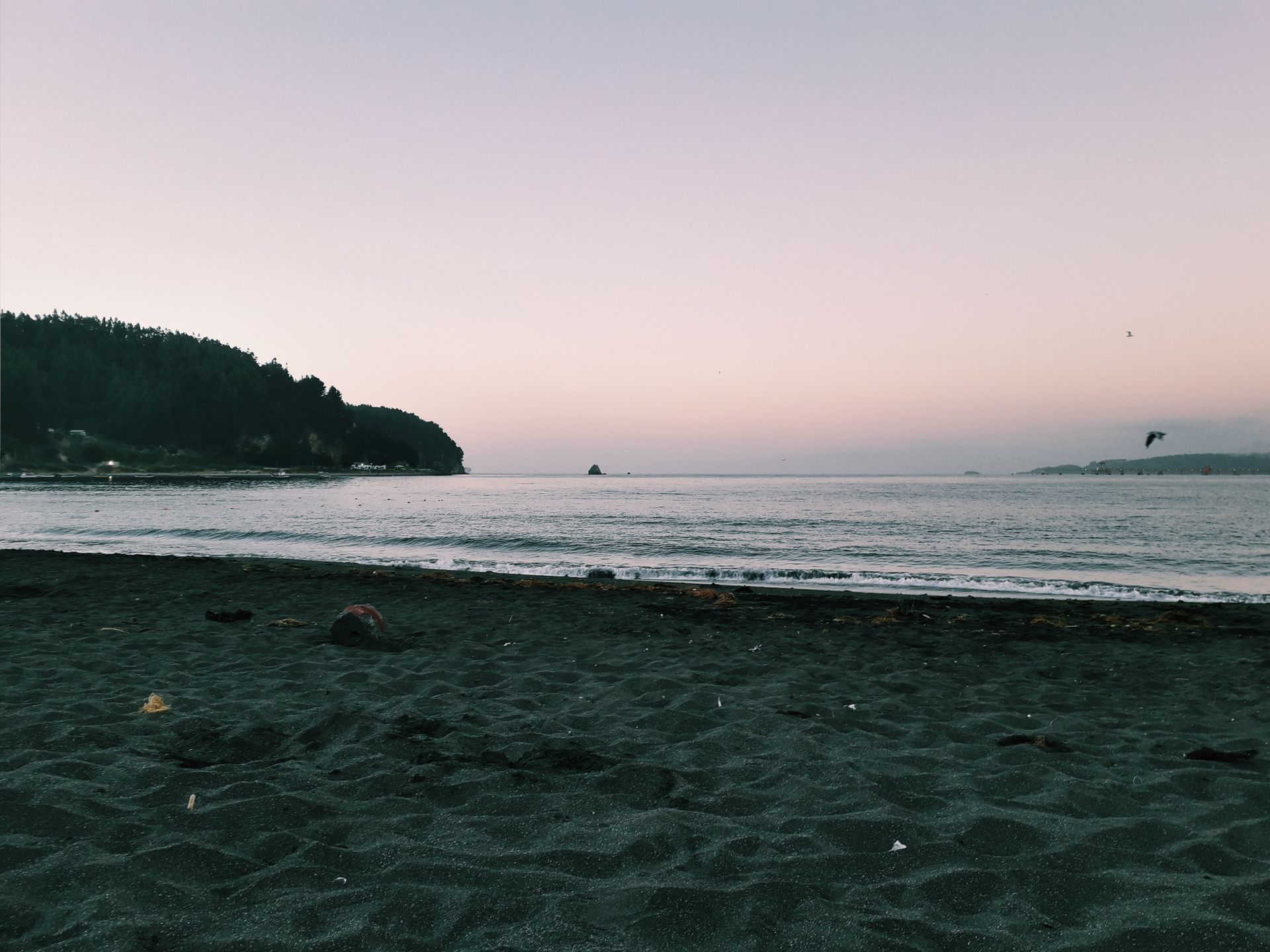Tranquil beach scene at Talcahuano, Chile during sunset with calm waves.