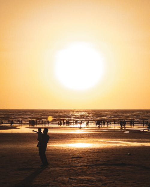 Fotografía De Silueta De Personas En La Playa Durante La Hora Dorada