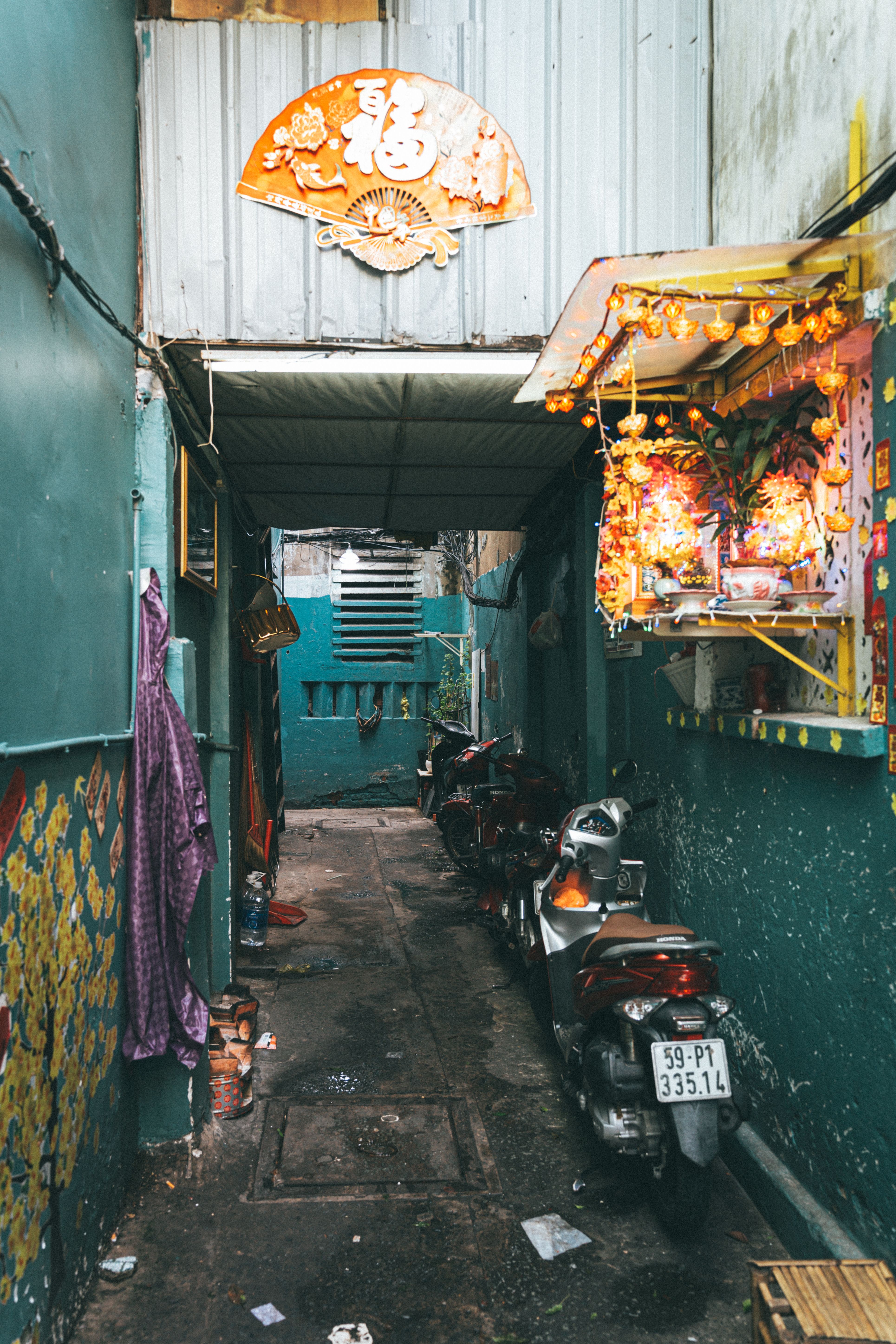 Vibrant alleyway in Ho Chi Minh City adorned with colorful decorations and parked motorbikes.