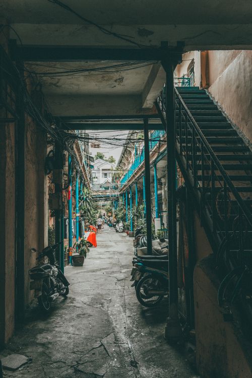 Free A bustling urban alleyway in Ho Chi Minh City featuring motorbikes and colorful architecture. Stock Photo