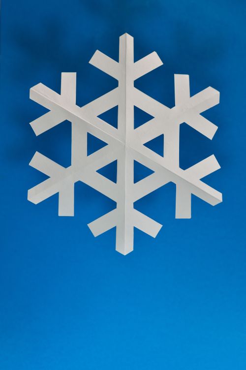 Free Handmade white paper snowflake contrasted against a bright blue backdrop. Stock Photo
