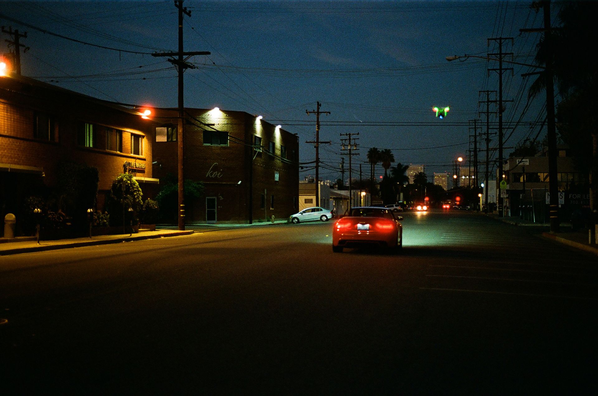A mysterious car driving on a quiet street at night with city lights.