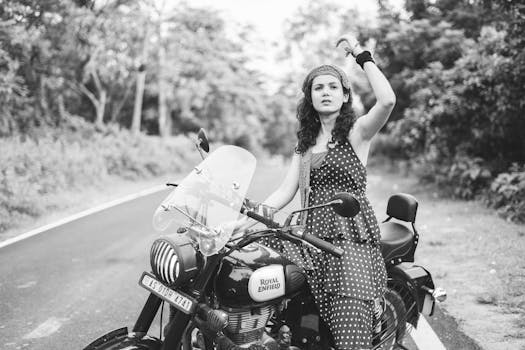 Stylish woman in polka dot dress sits on Royal Enfield motorcycle, Guwahati, India.