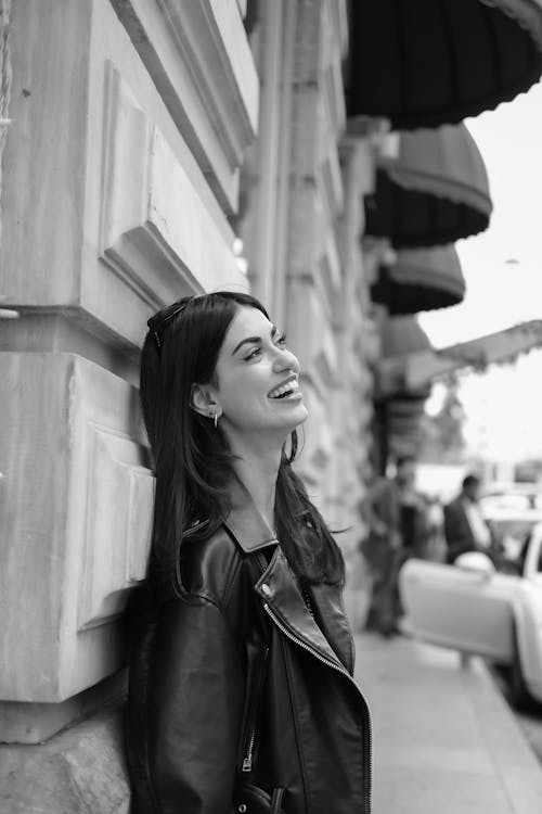 A woman in a leather jacket leaning against a wall