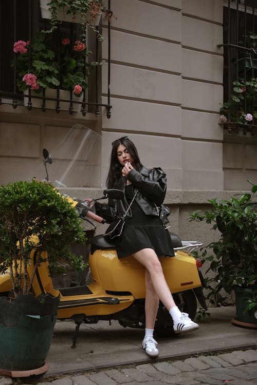 A woman sitting on a scooter with a cigarette