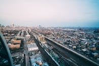 从空中俯瞰，繁华的城市景观中，道路和摩天大楼沐浴在日光下