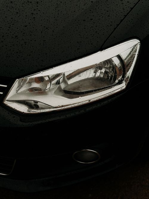 Free Detailed close-up of a car headlight covered in raindrops showcasing automotive design. Stock Photo
