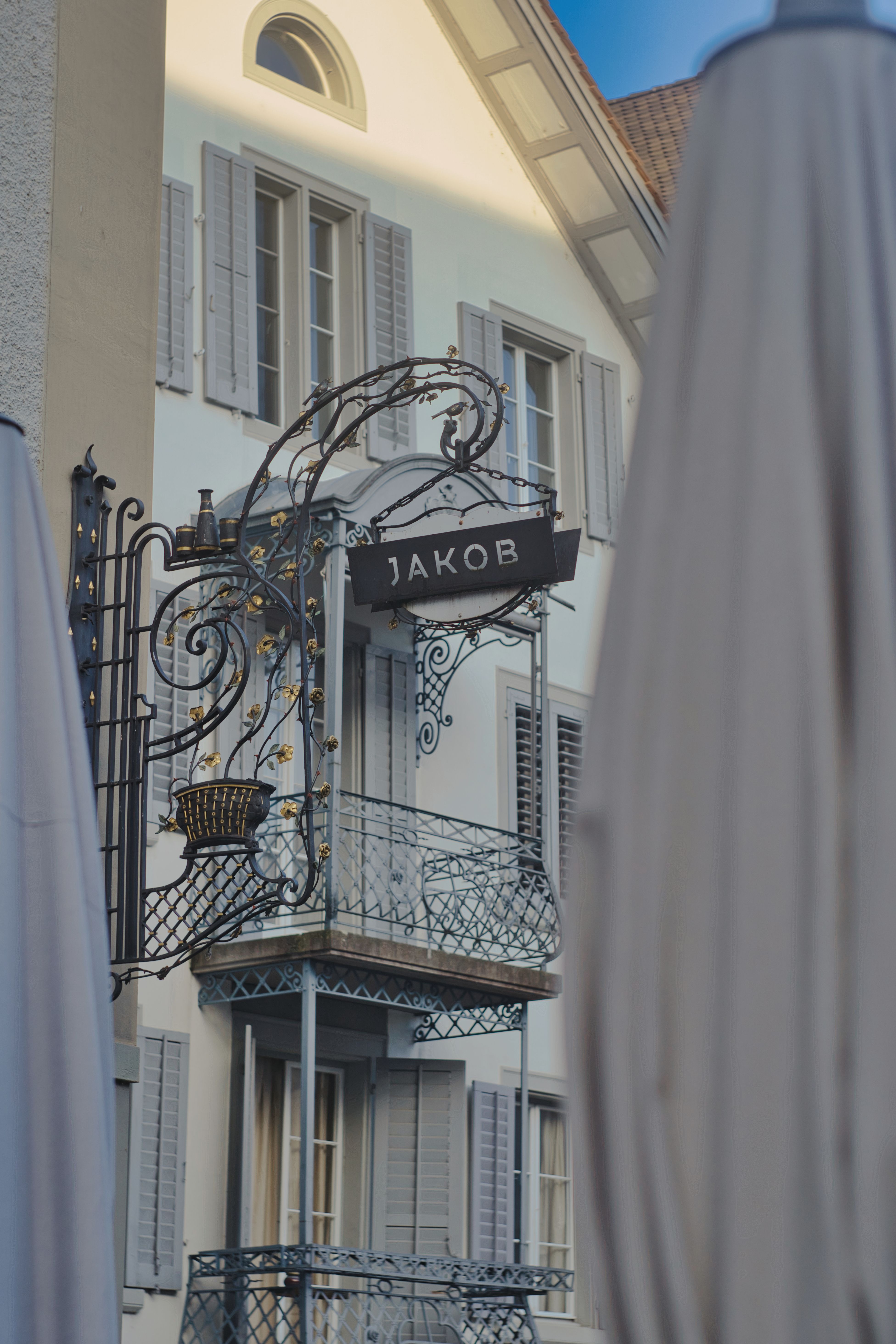 A beautifully designed building facade featuring intricate wrought iron balconies and an elegant sign.