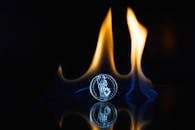 一枚硬币以反光表面映衬戏剧性的火焰，呈现出炽热的抽象艺术