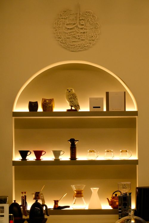 Free A stylishly lit shelf displays porcelain mugs, an owl figurine, and other decor. Stock Photo