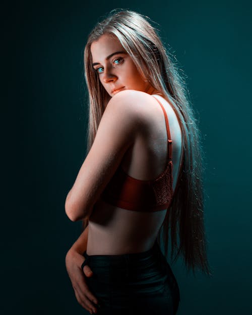 Side View Photo of in Bra Standing In Front of Blue Background