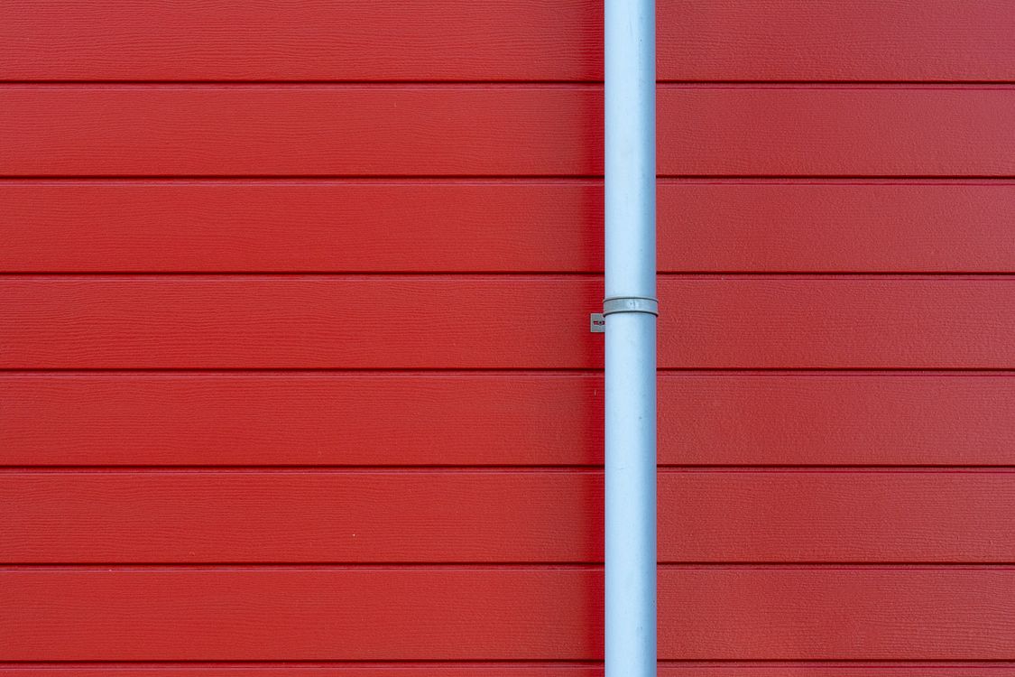 Clean white seamless rain gutter mounted on a red wall