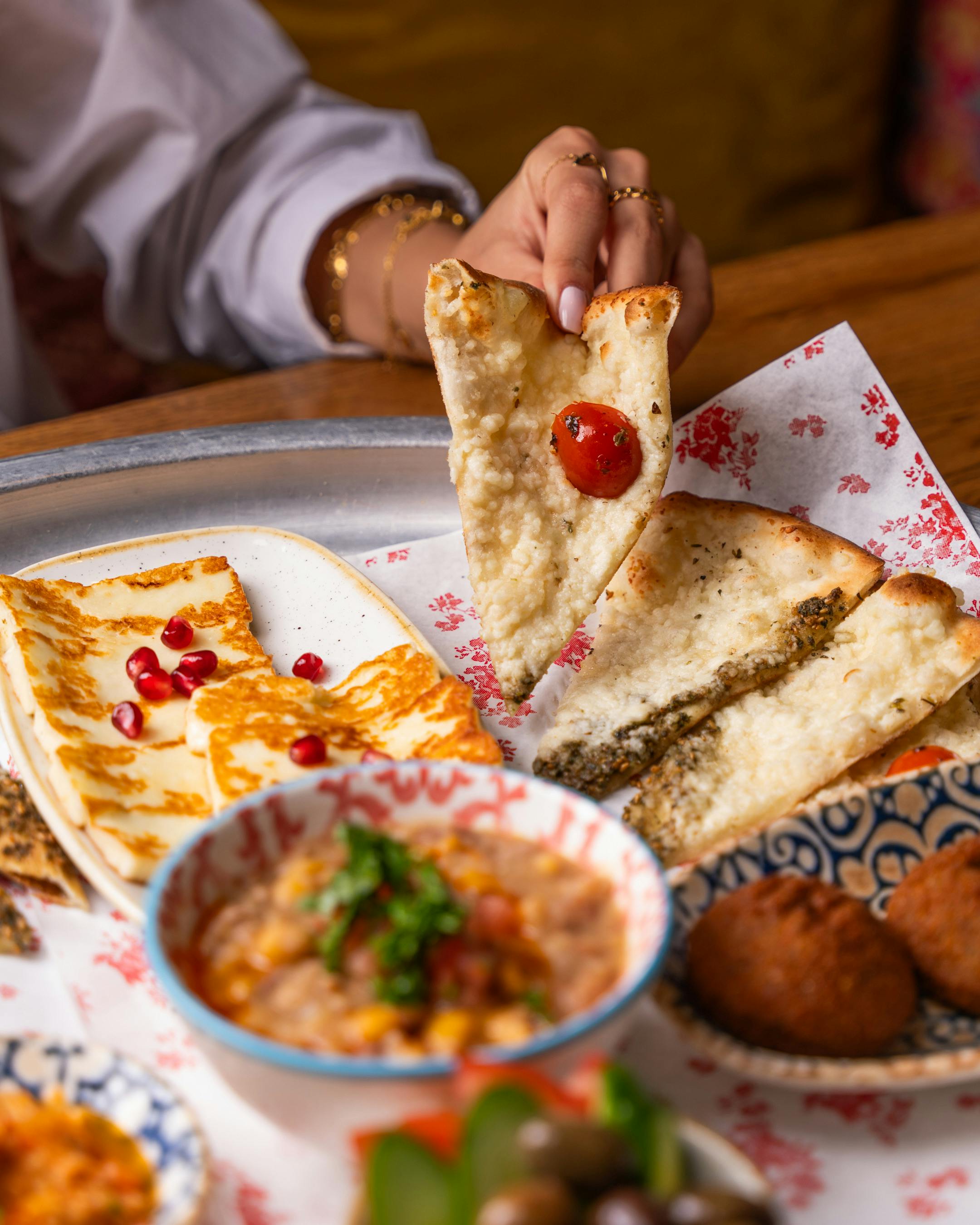 A selection of Middle Eastern dishes featuring flatbread, cheese, and dips at a restaurant.