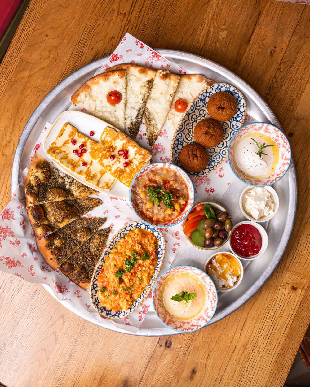 Colorful Middle Eastern mezze platter featuring flatbreads, hummus, falafel, and more.
